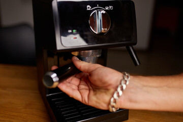 Female hands holding portafilter and making fresh aromatic coffee at home using a modern coffee maker, Male barista hand making espresso from ground coffee maker at modern cafe.