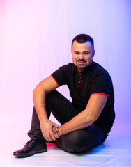 portrait of a man in a black t-shirt, jeans in the studio. Italian macho on a colored background, looks at us.