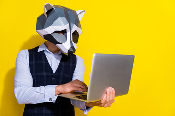 Photo of focused guy hold netbook write code wear raccoon mask vest isolated yellow color background