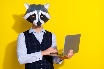 Photo of office employer guy prepare pc project texting wear raccoon mask vest isolated yellow...