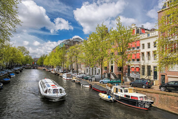 Amsterdam city with tourist boats on canal during springtime in Netherlands.