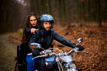 Plakat Couple of motorcyclists with a chopper in the woods in the fall.