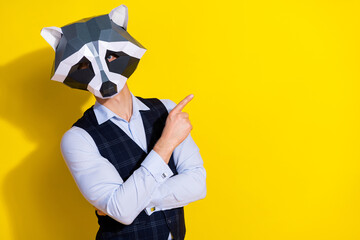 Fototapeta na wymiar Photo of promoter man direct finger empty space wear raccoon polygonal mask vest isolated yellow color background
