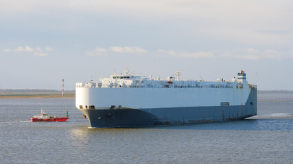 Port of Antwerp, Belgium - 11 24 2021: Pure car carrier leaving the port and bound for sea. Ro-ro vessel with the cargo of cars underway to the next destination.