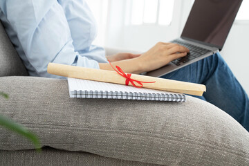 Diploma scroll is on notebook. Close-up. Female person working on computer, laptop keyboard on background. Concept for online student, distance learning, new profession, secondary education, freelance