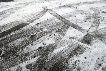 Snow on asphalt road with car imprints.