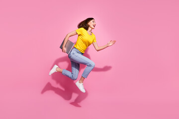 Photo of cute pretty young lady dressed yellow clothes smiling hurrying jumping carrying modern gadget isolated pink color background