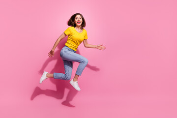 Photo of impressed sweet young woman wear yellow outfit jumping high running fast empty space smiling isolated pink color background