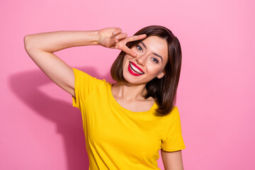 Portrait of attractive funky brown-haired cheerful girl showing v-sign having fun isolated over...