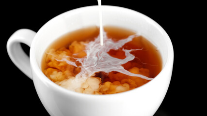 Tea with milk. Pour milk in tea, close up