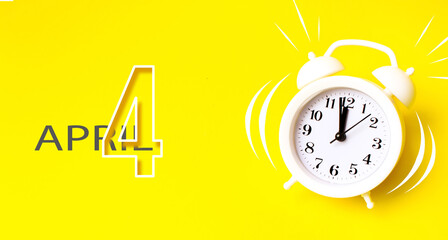 April 4th. Day 4 of month, Calendar date. White alarm clock with calendar day on yellow background....