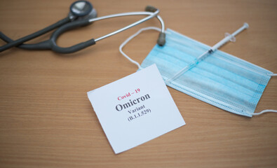 Covid 19 Omicron variant concept. Displaying note on a paper of the new variant along with facemask...