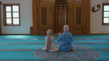  Muslim mother and her little daughter pray in a hijab mosque. Little girl and her mother praying to god.Islam, religion and worship concept.