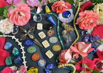 Still life with magic objects, runes, crystals with chakra symbols and flowers on witch table.