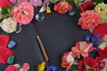 Still life with open diary with black pages, flowers, crystals and copy space, top view.