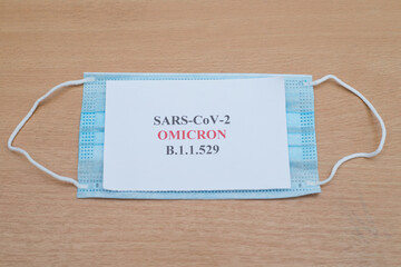 Sars-CoV2 Omicron Variant b.1.1.529 written on a piece of paper placing on blue color facemask on...