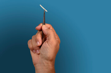 hand holding a hormonal implant with tweezers