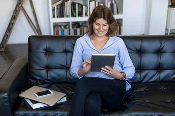 Attractive young woman holding a tablet at home