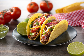 Traditional Mexican tacos with meat and vegetables on wooden table	