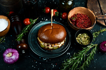 Juicy burger in the hands of the chef. Burger with bacon, pickles and cheese sauce. Fast food concept.