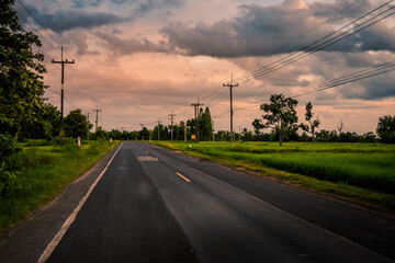 Fototapeta premium Rural roads with fields and skies background.Country Road.Paddy rice field green grass on beautiful blue sky background and road , home or village