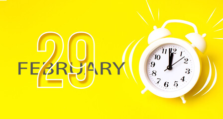 February 29th. Day 29 of month, Calendar date. White alarm clock with calendar day on yellow...