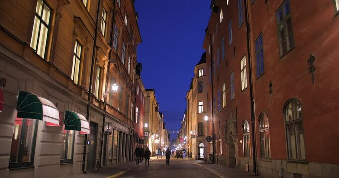 People Walking On The Street Of Gamla Stan, The Old Town Of Stockholm In Sweden, At Night. low angle, slider shot 4k