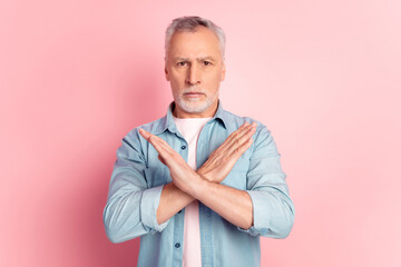 Photo of senior man show hands crossed no stop rejection symbol protest isolated over pink color background