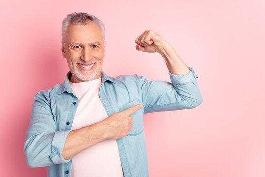Photo of senior man indicate fingers arms muscles training sportive isolated over pink color background