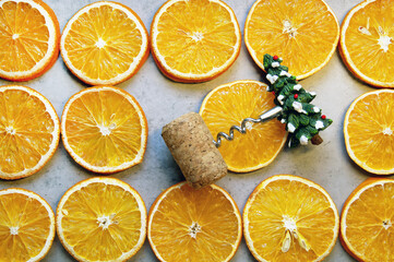Naklejka na ściany i meble A corkscrew in the form of a spruce is wound on a cork lying on dried oranges
