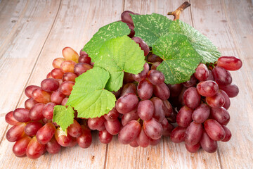 Red grape with leaves on wooden background, Bunch of fresh red grapes with leaves.