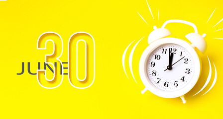 June 30th. Day 30 of month, Calendar date. White alarm clock with calendar day on yellow background. Minimalistic concept of time, deadline. Summer month, day of the year concept.