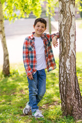 Cheerful boy portrait standing in city park while looking at camera