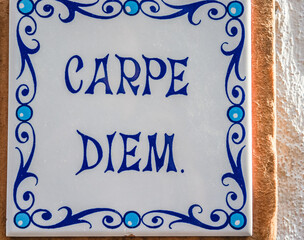 a wall tile with a Carpe Diem sign and blue ornaments