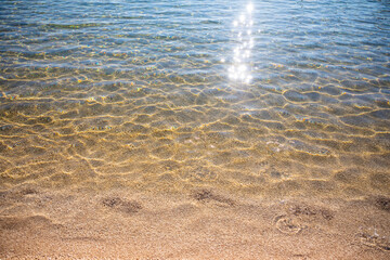 Ripples on surface of sand sea bottom, clear and calm blue sea water, fishes in water, nature texture