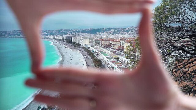 Woman makes a frame with fingers on the beach on the Cote d'azur Nice, Bay of angels (Baie-des-Anges), Provence, France