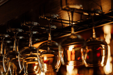 Clean wine glasses prepared by bartender and hung on the bar at a restaurant or cafe. Glasses prepared for a party at the bar. selective focus