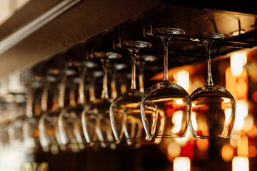 Clean wine glasses prepared by bartender and hung on the bar at a restaurant or cafe. Glasses prepared for a party at the bar. selective focus