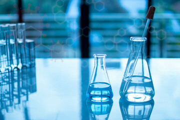 Chemistry experiment concept in science laboratory, monkeypox virus. Two science flasks of different sizes contain different chemicals. The chemicals are in many glass tubes on the table and blurred.