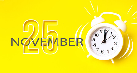 November 25th. Day 25 of month, Calendar date. White alarm clock with calendar day on yellow background. Minimalistic concept of time, deadline. Autumn month, day of the year concept.