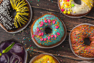 Top view of donuts in various colors and flavors on wooden table