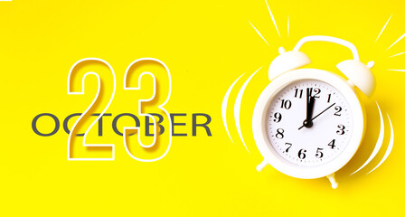 October 23rd. Day 23 of month, Calendar date. White alarm clock with calendar day on yellow...