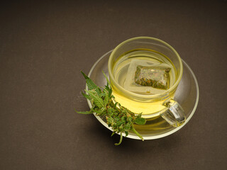 Cannabis tea in a teacup and marijuana buds flowers on a gray background