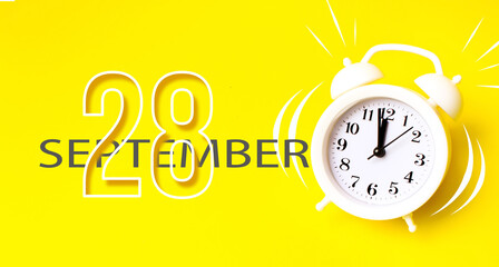 September 28th. Day 28 of month, Calendar date. White alarm clock with calendar day on yellow background. Minimalistic concept of time, deadline. Autumn month, day of the year concept.