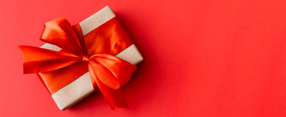 Banner made of Present box with red bow on red background. Flat lay, top view, copy space.