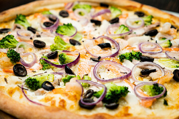Pizza with seafood, olives, broccoli and onions