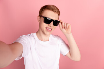 Photo of young handsome guy shoot selfie hand touch sunglass vacation summer isolated over pink color background