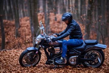 Handsome biker in the forest in autumn.