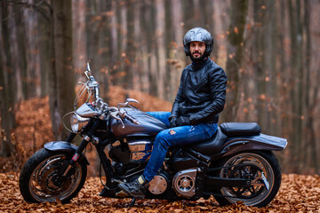 Handsome biker in the forest in autumn.