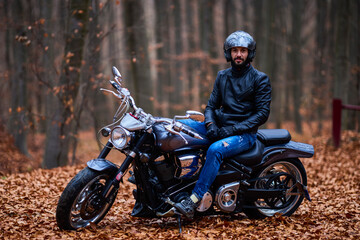 Handsome biker in the forest in autumn.